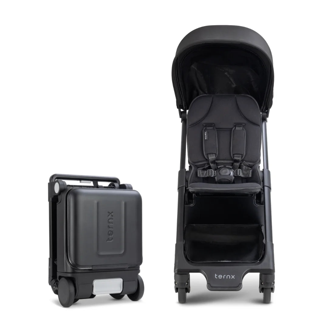 A black TernX stroller shown upright with its matching rolling suitcase beside it.