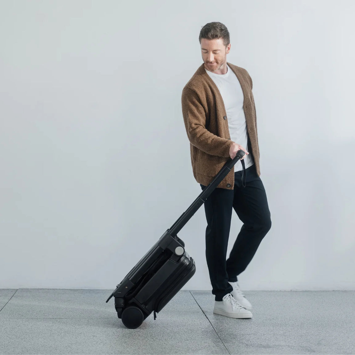 Dad pushing the TernX Carry On Luggage Stroller with toddler through an airport terminal