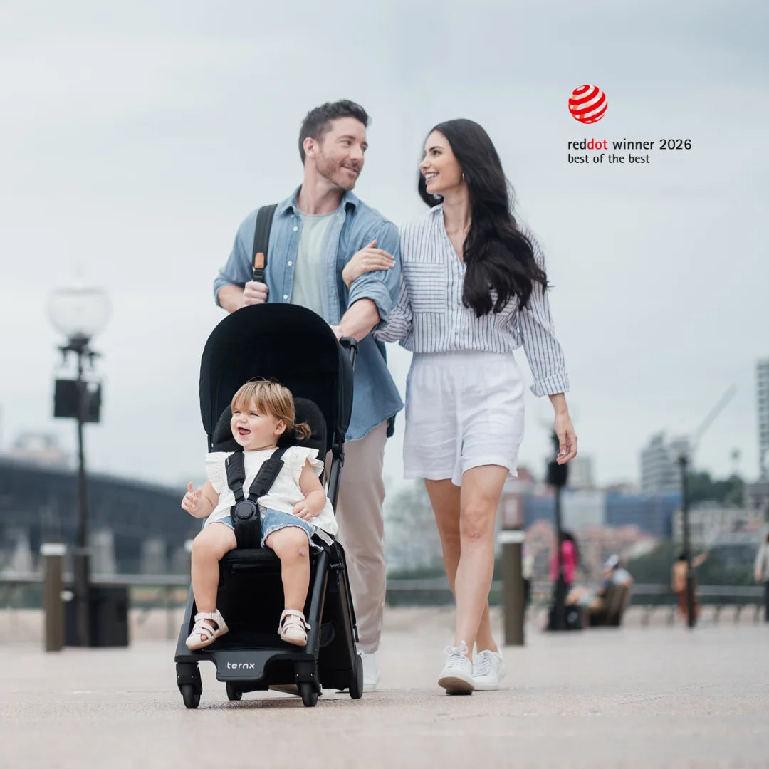 Family with a child in a stroller walking outdoors, with Red Dot Award best of the best stroller